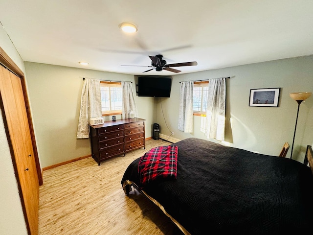 bedroom featuring multiple windows, a baseboard heating unit, and baseboards