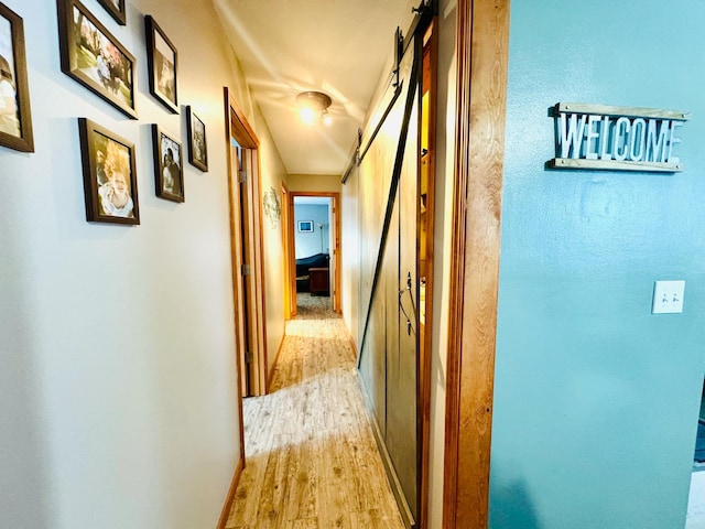 corridor with a barn door and light wood-style floors