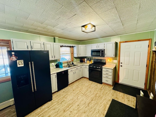 kitchen featuring light wood finished floors, a baseboard radiator, black appliances, and a sink