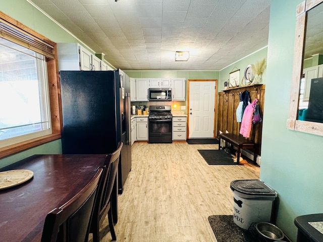 kitchen with white cabinets, black appliances, light countertops, and light wood-style floors