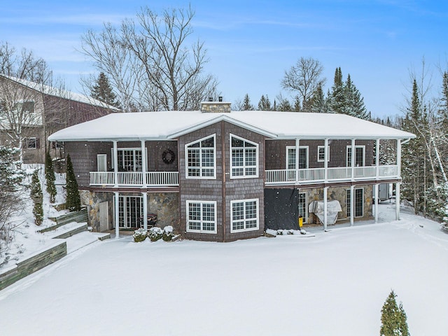 snow covered house with a balcony and a chimney