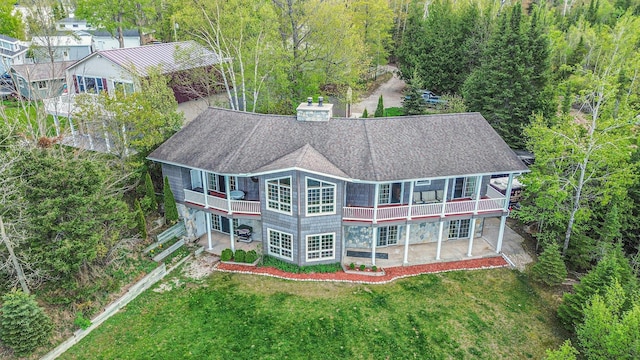 5560 Chestnut Dr, Cheboygan, MI 49721 - back of house with roof with shingles, a yard, a balcony, a chimney, and a wooded view