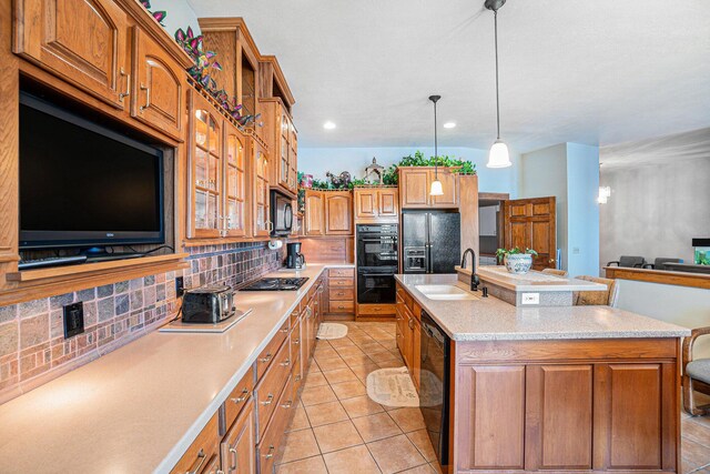 5560 Chestnut Dr, Cheboygan, MI 49721 - kitchen with black appliances, tasteful backsplash, light countertops, a sink, and an island with sink