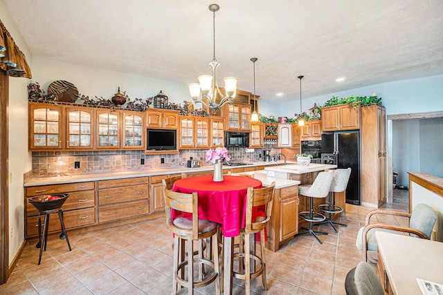 5560 Chestnut Dr, Cheboygan, MI 49721 - kitchen with black appliances, a center island, tasteful backsplash, a chandelier, and a breakfast bar