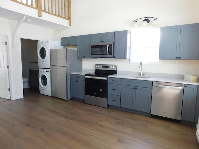 kitchen with stacked washer and clothes dryer, stainless steel appliances, light countertops, and a sink