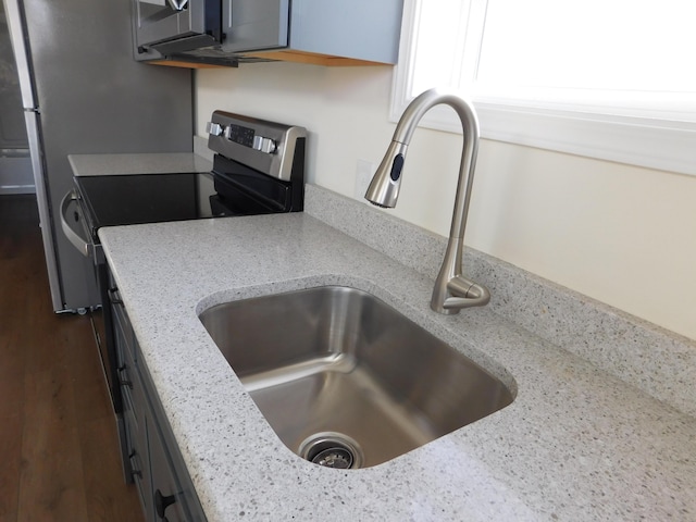 kitchen with light stone counters, dark wood-style floors, and a sink