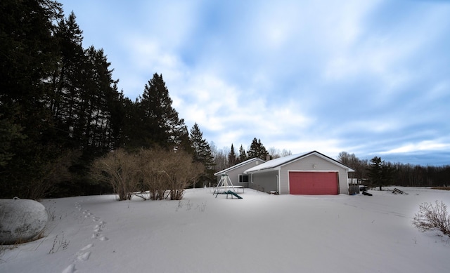 snowy yard featuring an outbuilding and an attached garage