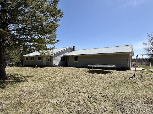6348 Zolner Rd, Cheboygan, MI 49721 - view of side of home featuring a chimney, metal roof, a yard, and a trampoline