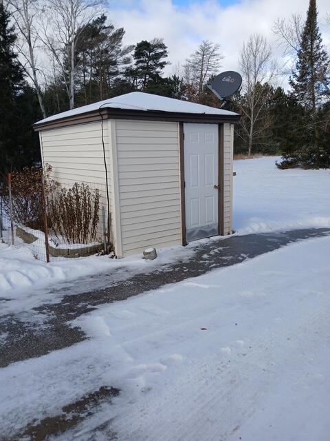 snow covered structure with a storage unit and an outdoor structure