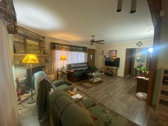 living area featuring a brick fireplace, wood finished floors, and ceiling fan