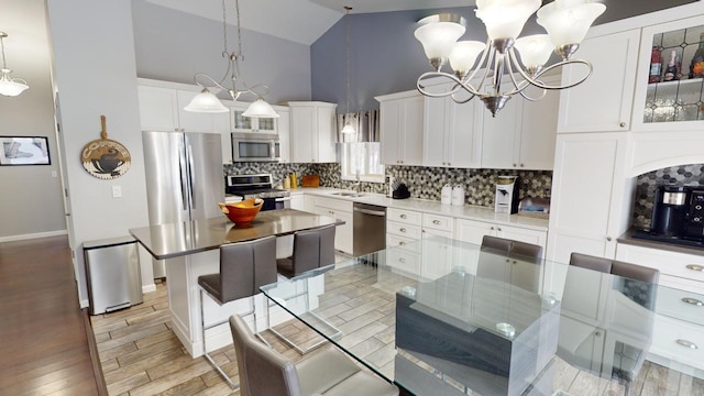 kitchen featuring a sink, stainless steel appliances, glass insert cabinets, tasteful backsplash, and a center island