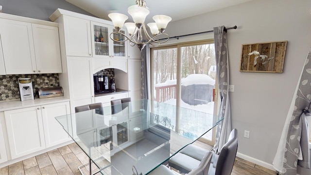 dining area with baseboards, an inviting chandelier, wood tiled floor, and vaulted ceiling