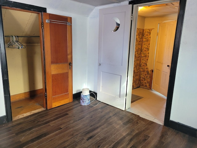 unfurnished bedroom featuring a closet, baseboards, and dark wood finished floors