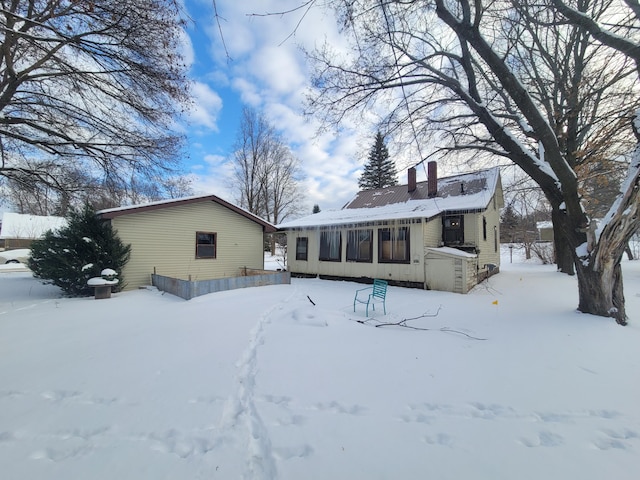 snow covered back of property featuring a chimney