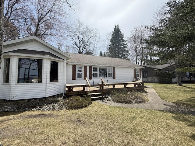 single story home with a shingled roof, a chimney, a deck, and a front yard