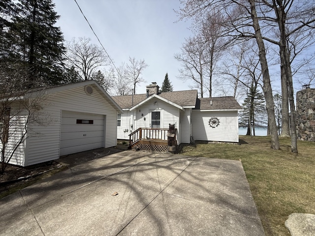 view of front facade with a garage, a front yard, roof with shingles, a chimney, and concrete driveway
