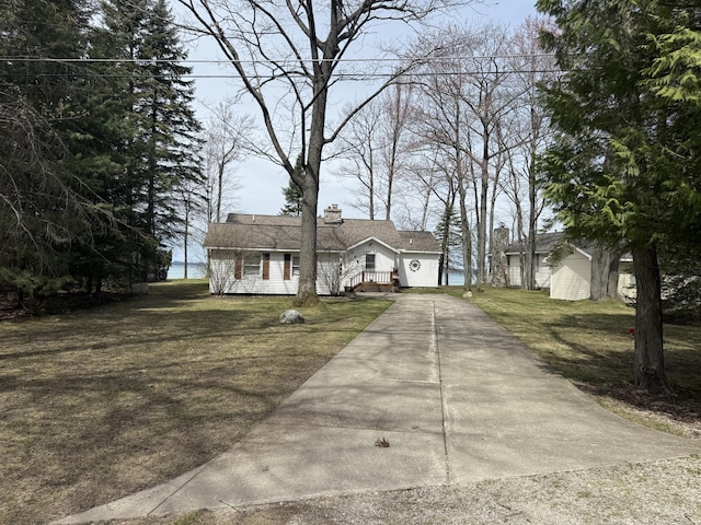 ranch-style home featuring a front lawn, a chimney, and concrete driveway