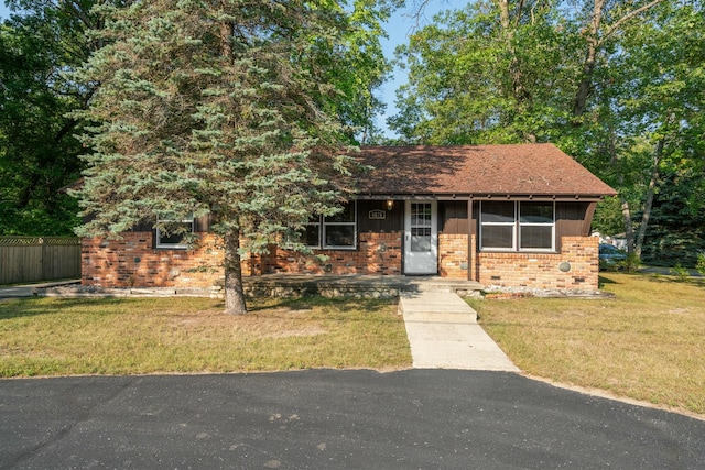 ranch-style home with brick siding, a front yard, and fence