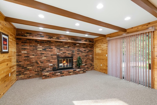 4878 S Straits Hwy, Indian River, MI 49749 - unfurnished living room with wooden walls, beamed ceiling, a brick fireplace, and carpet