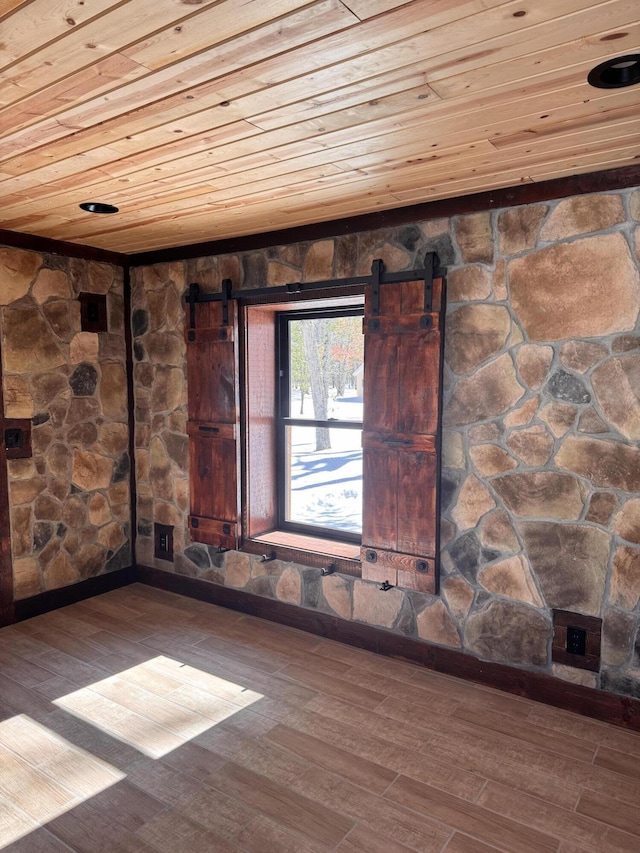 unfurnished room with a barn door, wood finished floors, and wooden ceiling