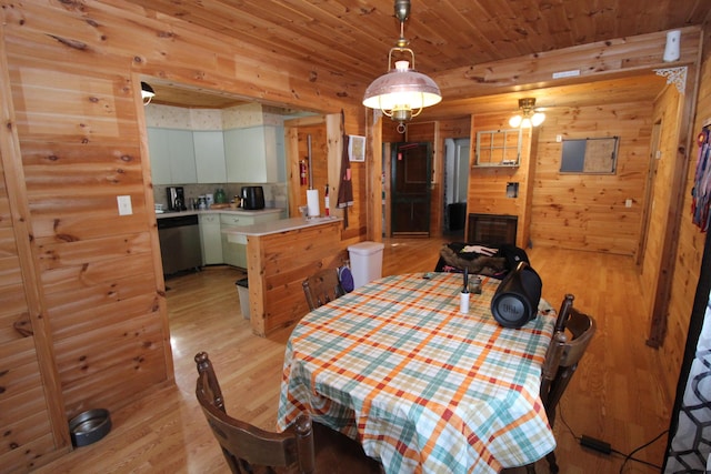 dining space with light wood-style flooring, wooden walls, and wood ceiling