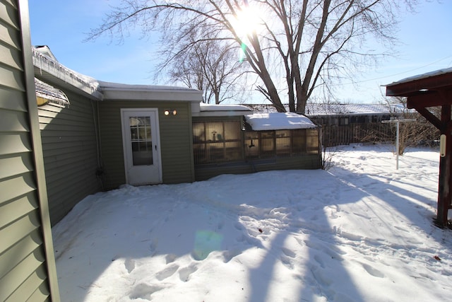 yard layered in snow with fence and a sunroom