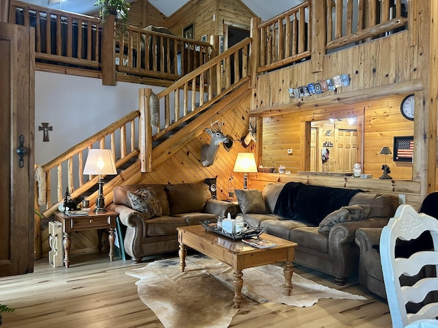 living room with stairs, hardwood / wood-style flooring, wooden walls, and a high ceiling