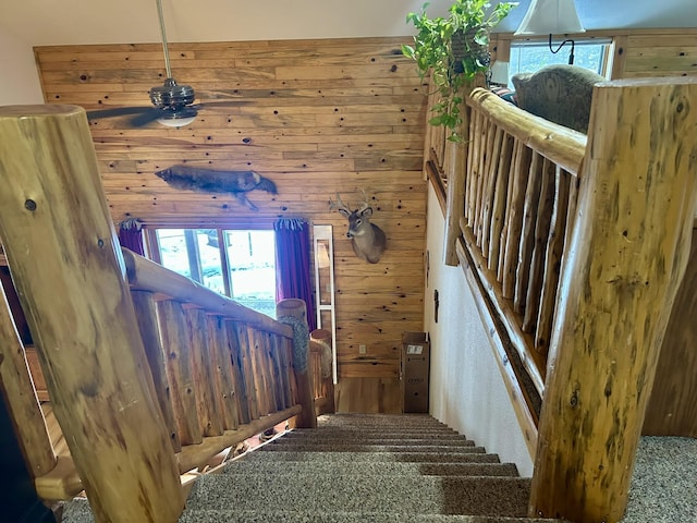 stairway with wooden walls and a ceiling fan