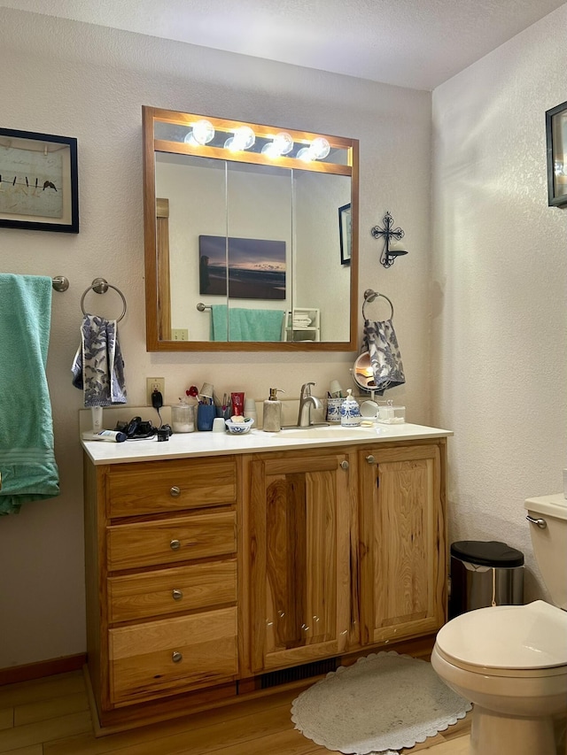 bathroom with vanity, toilet, and wood finished floors