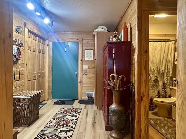 mudroom with wood finished floors, visible vents, and wood walls