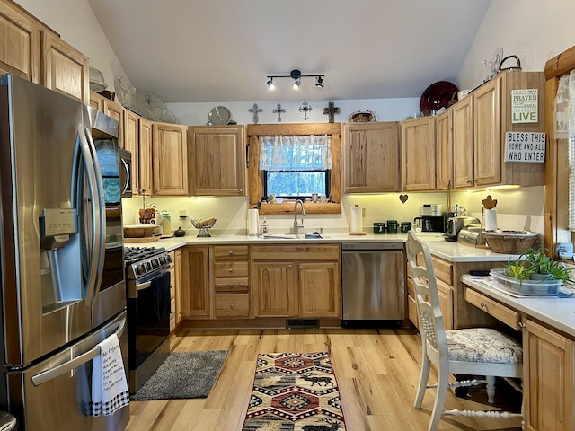 kitchen with lofted ceiling, a sink, stainless steel appliances, light countertops, and light wood-type flooring