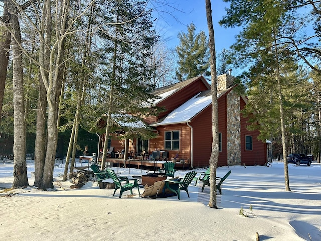 exterior space featuring log veneer siding, a chimney, and a patio area