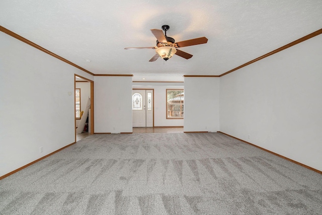 carpeted empty room with ceiling fan, a textured ceiling, baseboards, and ornamental molding