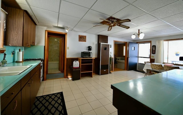 kitchen featuring a sink, a paneled ceiling, stainless steel stove, and ceiling fan