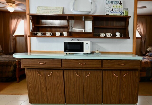 kitchen featuring open shelves, white microwave, a ceiling fan, and light countertops