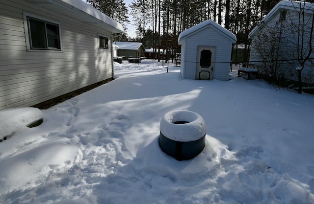 snowy yard featuring a storage shed and an outdoor structure