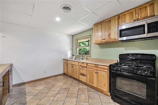 kitchen with visible vents, a sink, stainless steel microwave, light countertops, and black range with gas cooktop