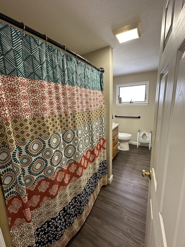 full bathroom with toilet, a textured ceiling, vanity, and wood finished floors