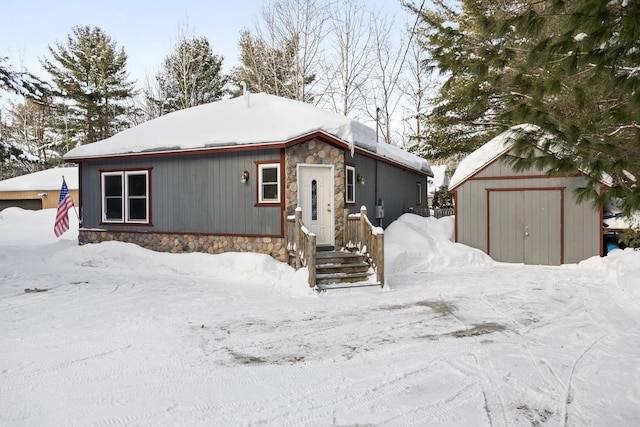 view of front of house featuring stone siding, a detached garage, a storage shed, and an outdoor structure