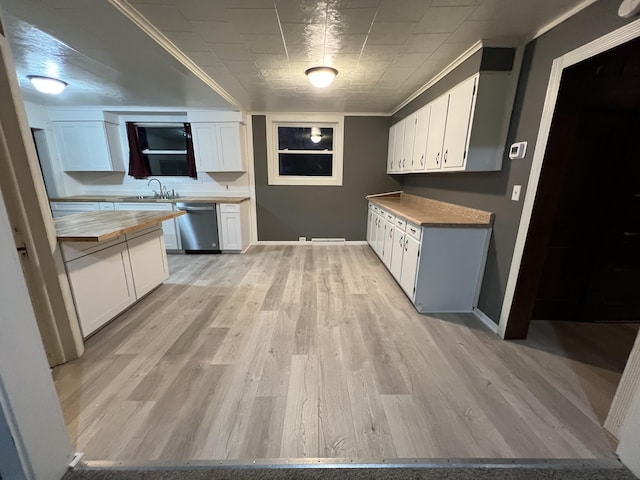 kitchen featuring light wood finished floors, stainless steel dishwasher, butcher block countertops, and white cabinetry