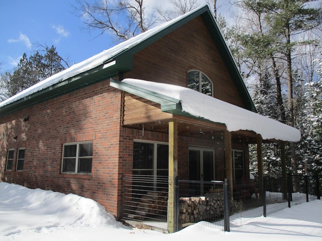 view of snowy exterior with brick siding