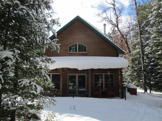 snow covered back of property featuring french doors