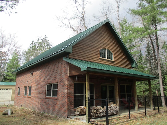 back of property featuring a garage, a patio, metal roof, and brick siding