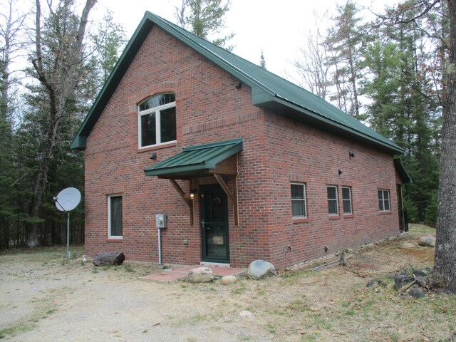 exterior space with brick siding and metal roof