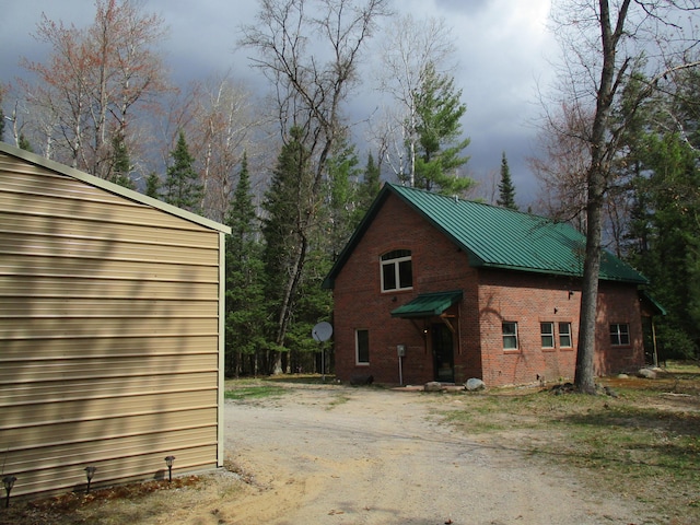 view of side of home featuring metal roof and brick siding