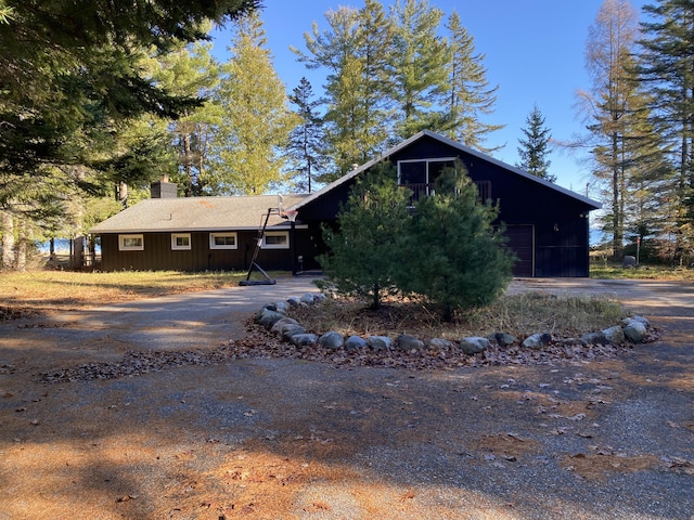 view of front of house featuring aphalt driveway, a garage, and a chimney