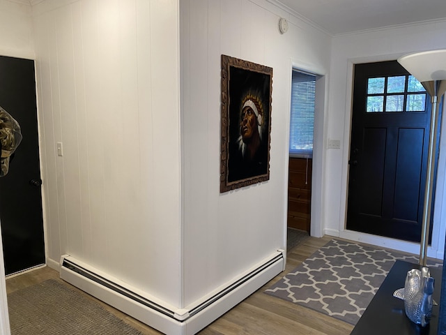 entrance foyer featuring a baseboard heating unit, wood finished floors, and ornamental molding