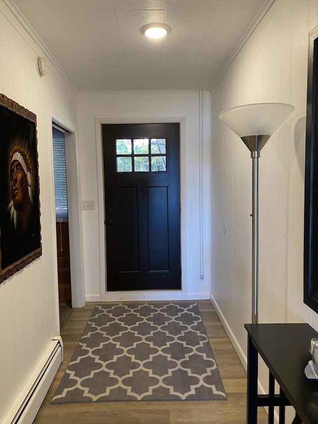 entryway with baseboard heating, ornamental molding, baseboards, and wood finished floors