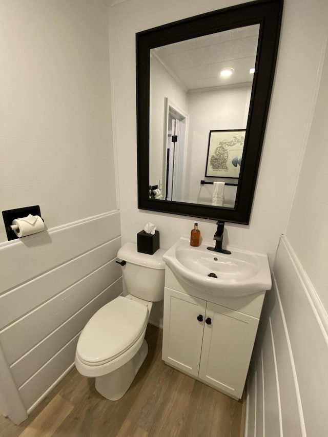 half bath with vanity, toilet, and wood finished floors