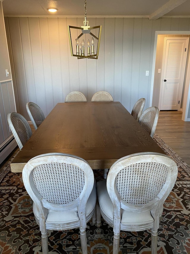 dining room featuring wood finished floors, a chandelier, and crown molding